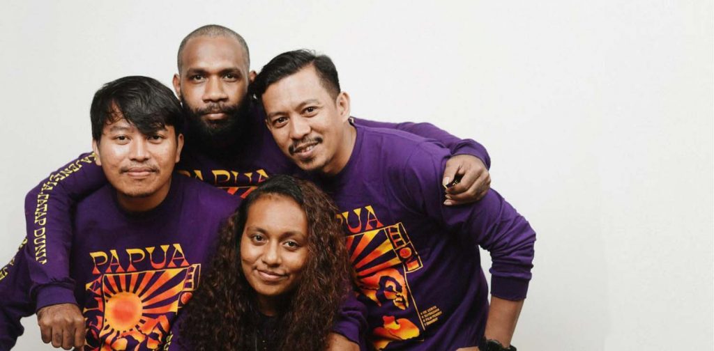 tiga pria dan satu wanita berpose bersama dalam t-shirt ungu jendela Papua, Empat pemenang proyek Jendela Papua