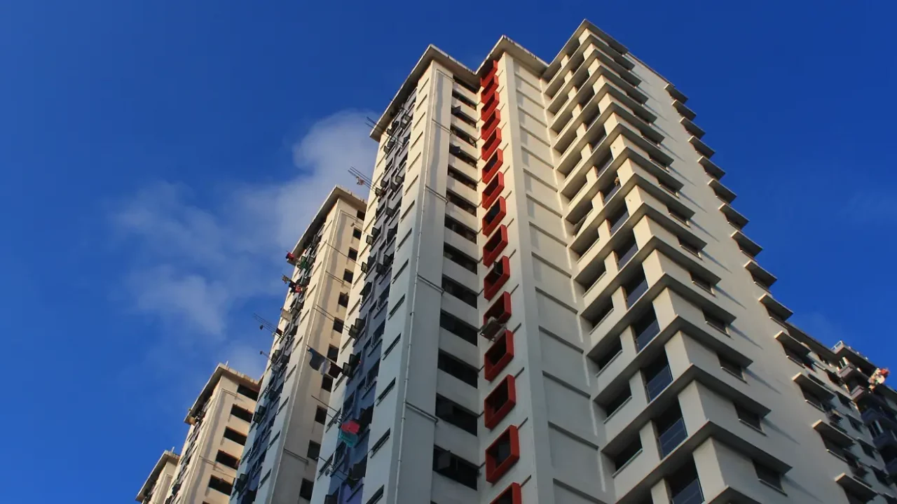 gedung perumahan bertingkat tinggi yang dipotret dari sudut rendah dengan latar belakang langit biru