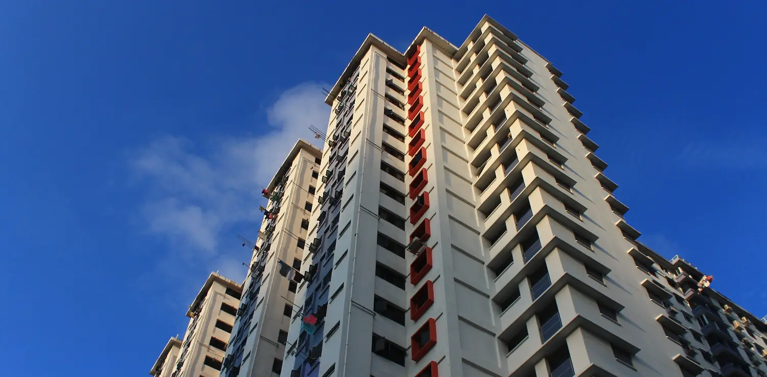 gedung perumahan bertingkat tinggi yang dipotret dari sudut rendah dengan latar belakang langit biru
