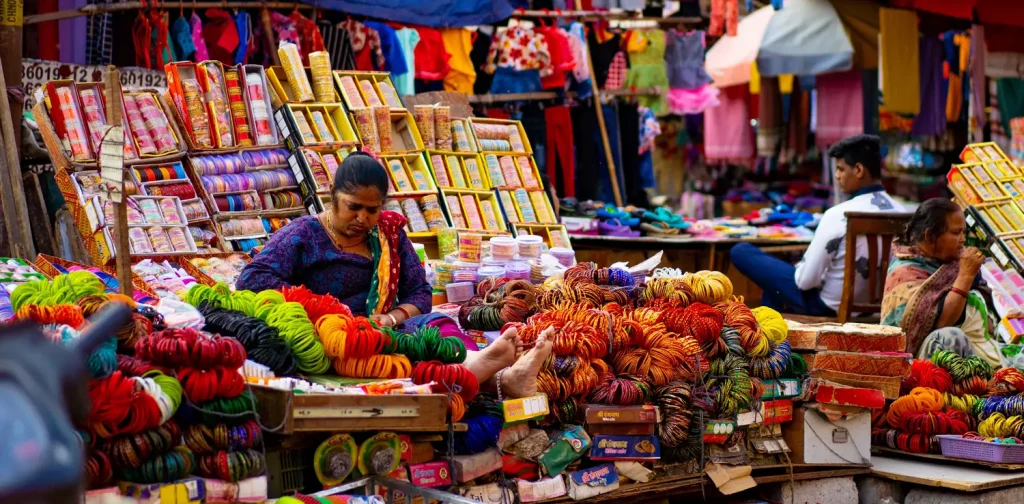 Perempuan berbaju biru di belakang pedagang kaki lima di Delhi, India