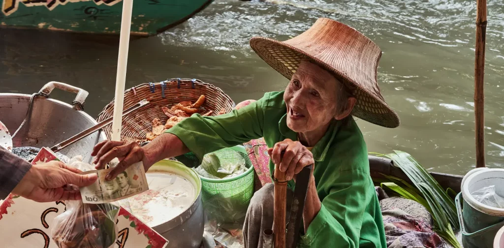 seorang wanita tua sedang menukar barang dengan uang di pasar terapung