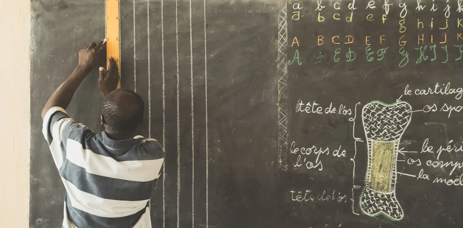 seorang guru laki-laki menggambar di papan tulis untuk mempersiapkan kelasnya