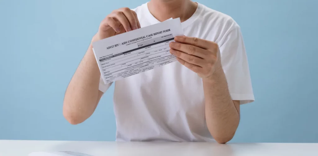 seorang pria berkaos putih memegang formulir tes HIV/AIDS.