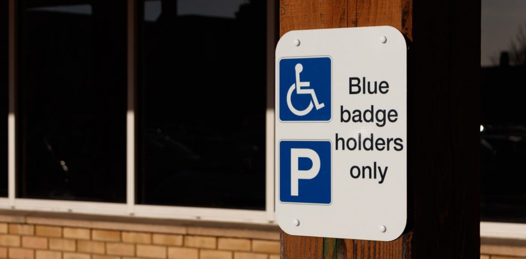 tanda parkir berwarna biru bertuliskan “Blue badge holders only” yang menunjukkan ruang khusus untuk penyandang disabilitas