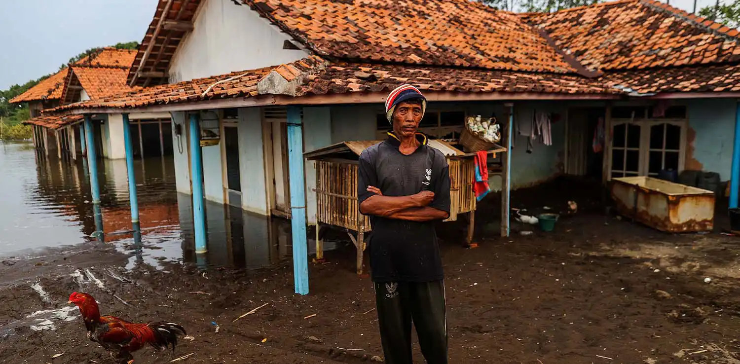 Seorang warga berdiri membelakangi rumah yang tenggelam akibat banjir rob di Pekalongan.