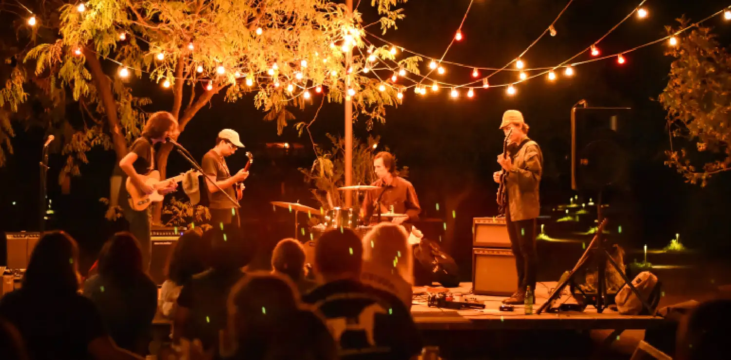 sebuah band beranggotakan empat orang tampil di hadapan penonton di bawah lampu jingga