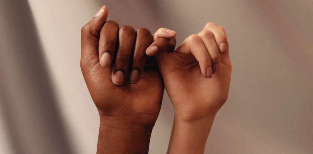 dua tangan dari ras yang berbeda saling mengaitkan jari kelingking
