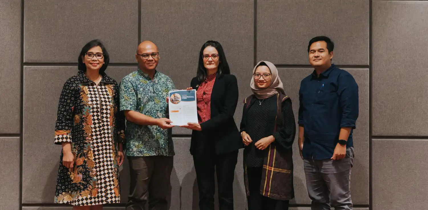 dua pria dan tiga perempuan menunjukkan policy brief dalam Peluncuran ringkasan kebijakan dalam Peluncuran Showcase dan Laporan Program Responsif Gender di Jakarta, Indonesia.