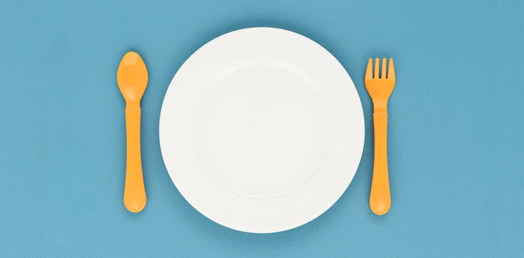 sebuah piring kosong dengan sendok dan garpu di sampingnya