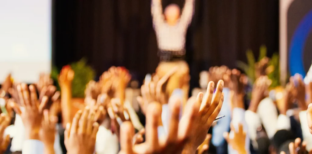 orang-orang mengangkat tangan di tengah konferensi.