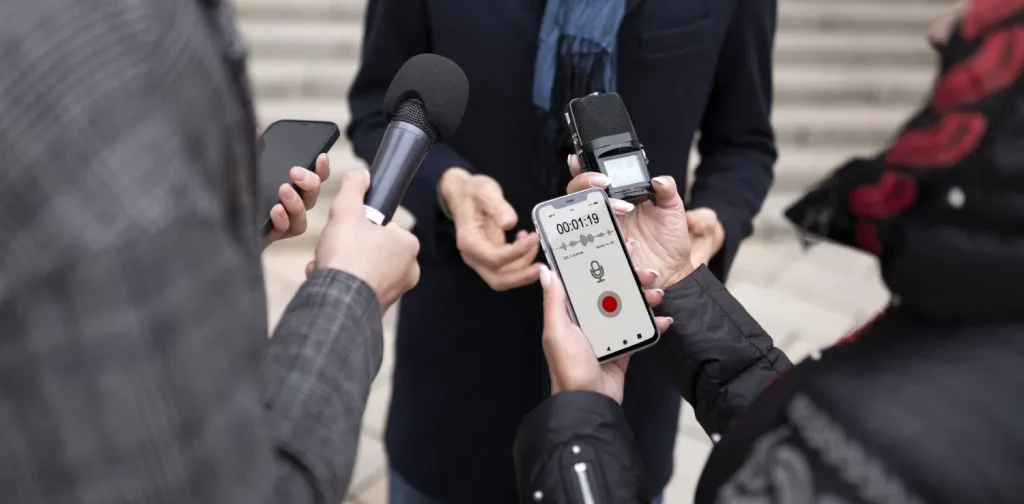 dua reporter memegang mikrofon dan alat perekam saat melakukan wawancara