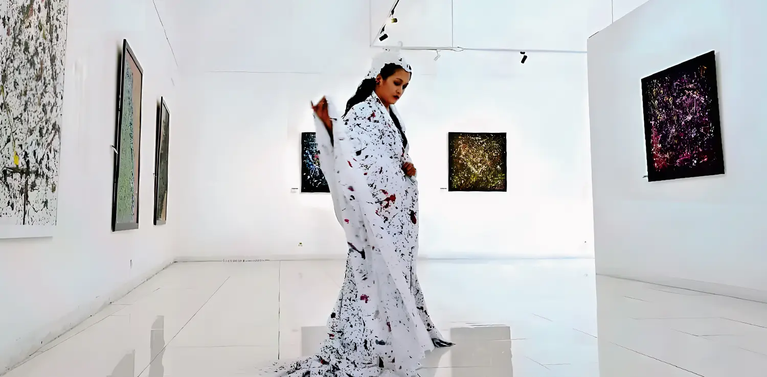 foto seorang perempuan sedang menari dengan jubah kanvas dengan corak bercak cat.