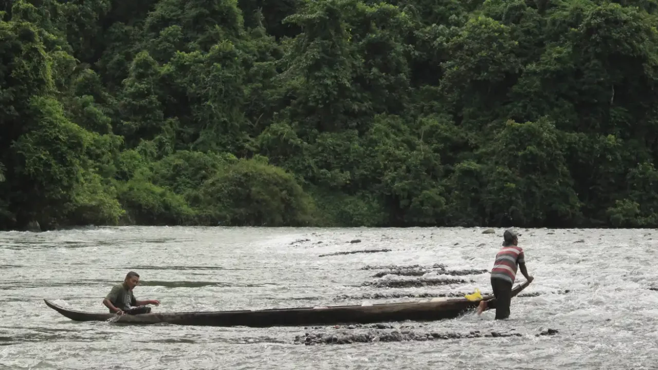 dua pria di tengah sungai dengan perahu kayu.