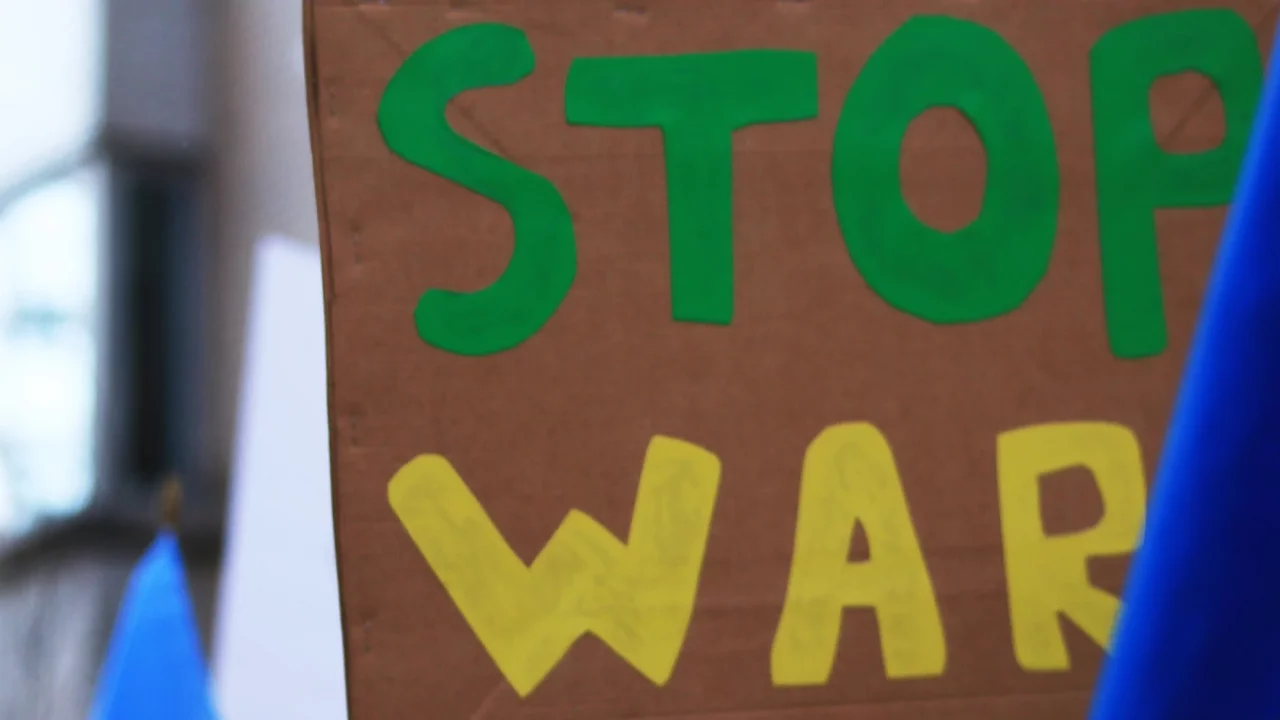 sebuah tangan memegang poster bertuliskan ‘stop war’.