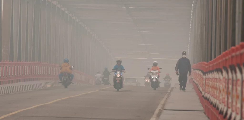 udara berkabut di jembatan dengan beberapa sepeda motor yang melintas