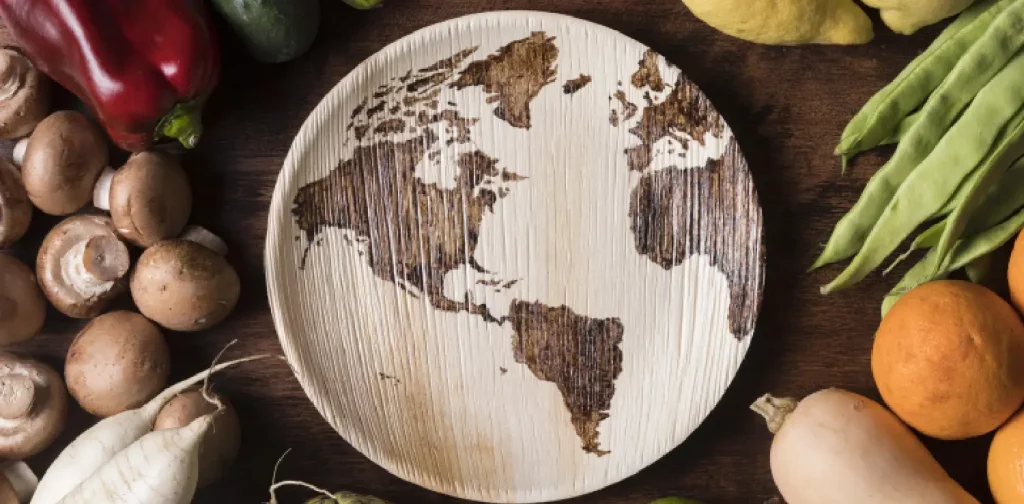 piring kayu dengan pola peta dunia dikelilingi oleh sayuran segar