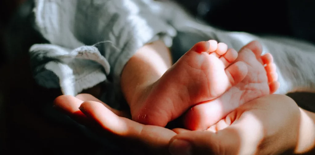 sebuah tangan ibu yang memegang kaki seorang bayi