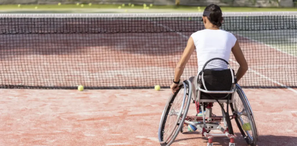 seorang perempuan dengan kursi roda di lapangan tenis