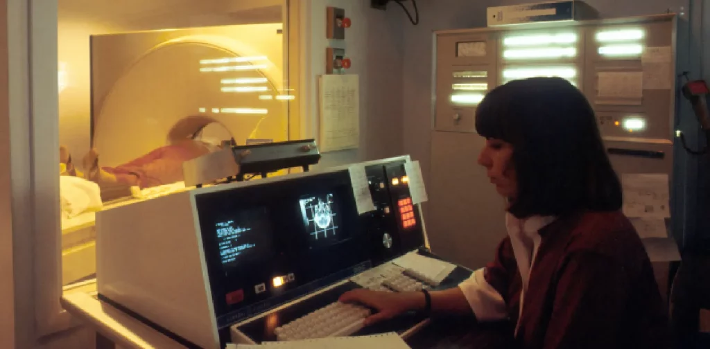 Seorang pasien berada di atas meja dan sedang diperiksa oleh pemindai tomografi komputer