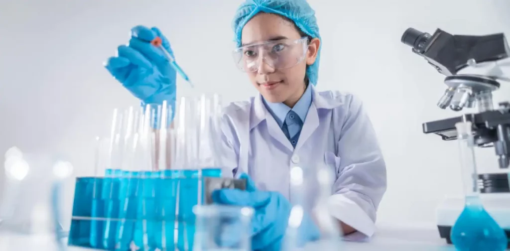 perempuan berjas lab memegang pipet dihadapan tabung reaksi