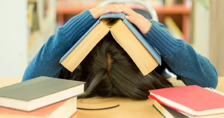 perempuan menelungkupkan kepala dengan buku di atasnya