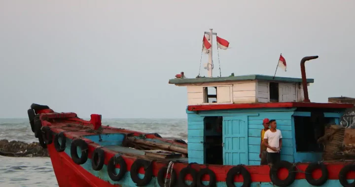 dua lelaki berdiri di atas kapal nelayan