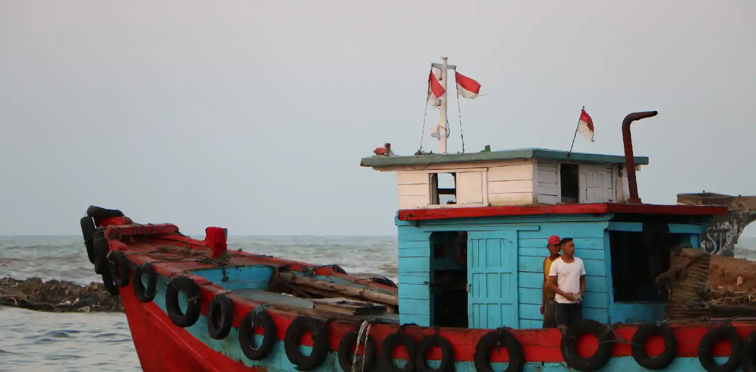 dua lelaki berdiri di atas kapal nelayan