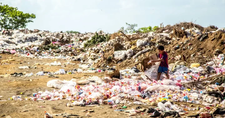 seorang anak laki-laki di antara tumpukan sampah di tempat pembuangan akhir