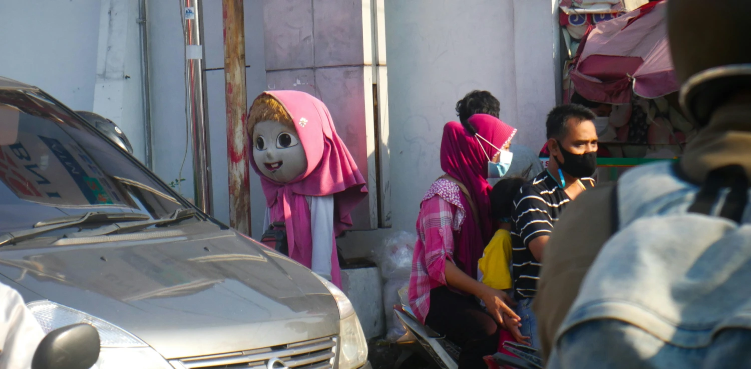 seorang pengemis berkostum badut di pinggir jalan di dekat mobil