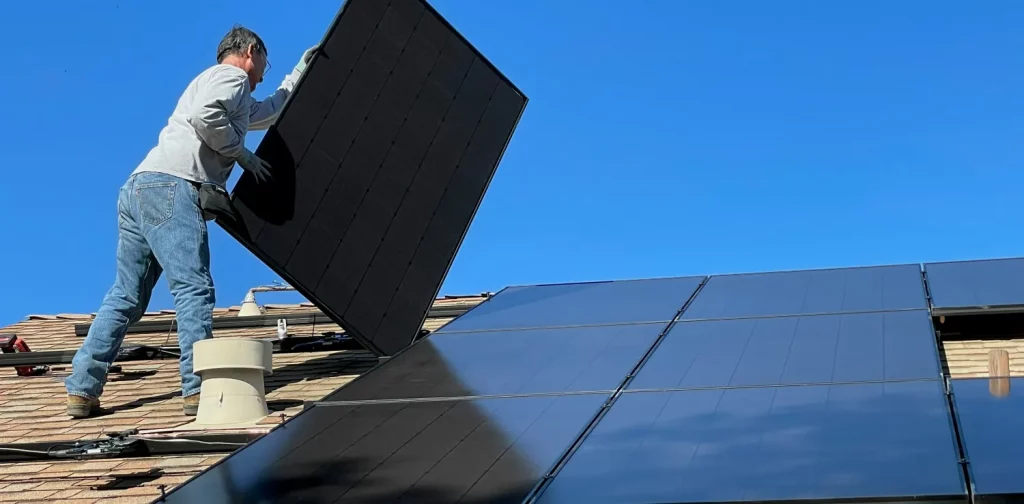 seorang pria memasang panel surya di atap