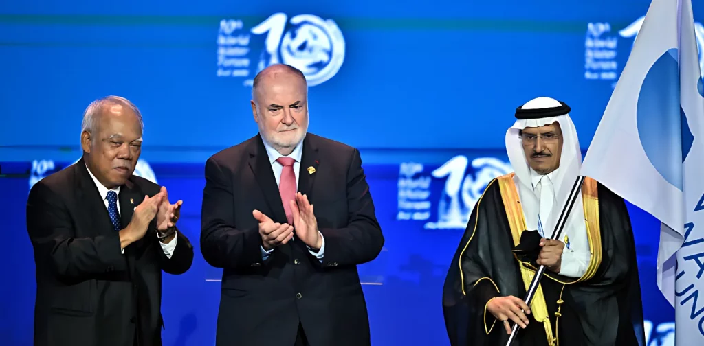 Tiga orang laki-laki berdiri di depan forum, mewakili Indonesia, World Water Council, dan Saudi Arabia, dengan perwakilan dari Saudi Arabia memegang bendera World Water Council.