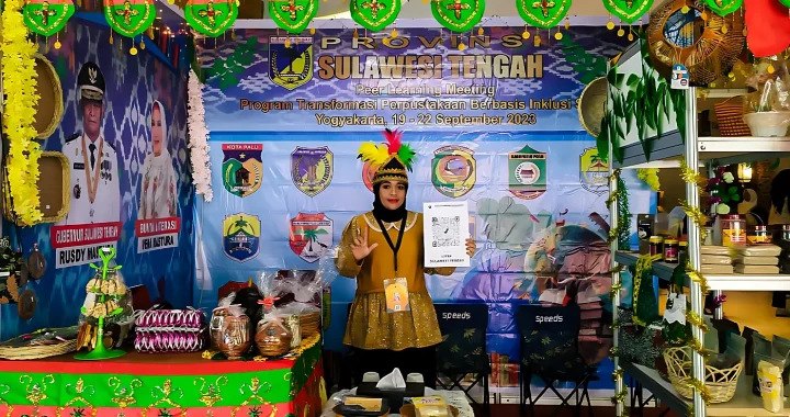 seorang perempuan memakai pakaian adat berdiri di sebuah stand Sulawesi Tengah