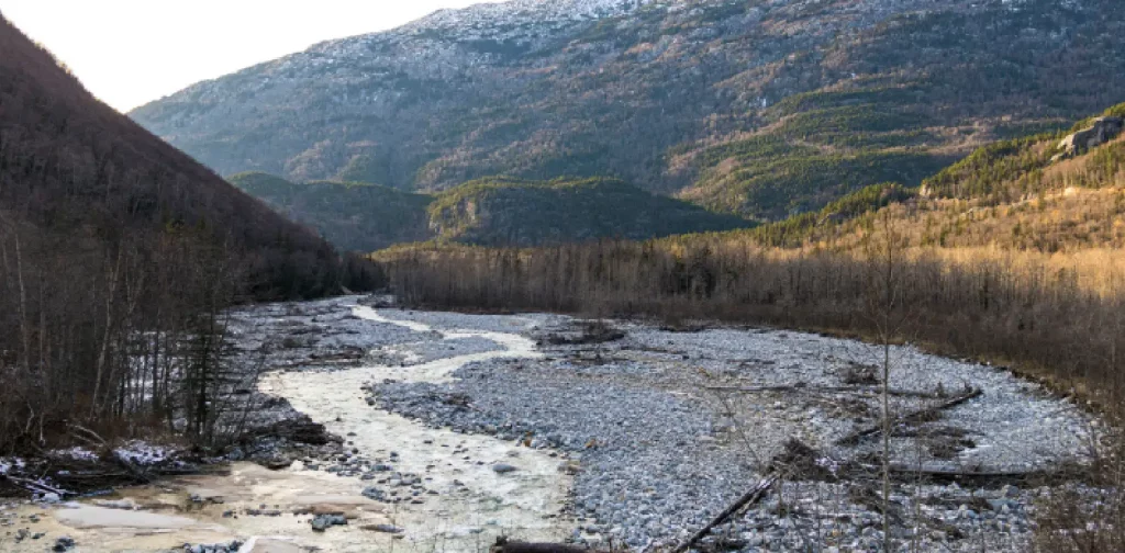 sungai yang mengering dengan bebatuan yang terlihat dengan latar belakang gunung