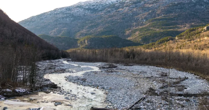 sungai yang mengering dengan bebatuan yang terlihat dengan latar belakang gunung