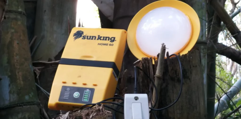 Sebuah baterai panel surya sederhana berwarna kuning, sebuah lampu, dan sebuah saklar, diletakkan di atas pohon.
