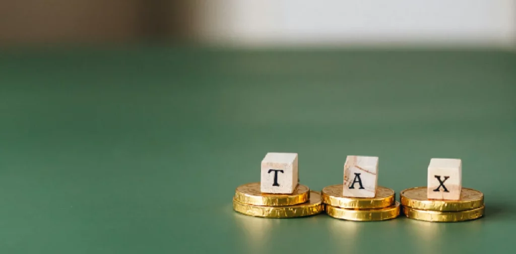 balok huruf membentuk kata ‘tax’ yang diletakkan di atas koin emas