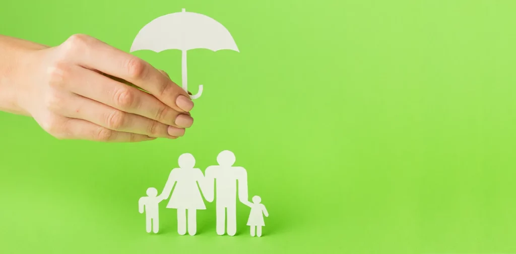 potongan kertas berbentuk keluarga yang dilindungi oleh payung yang dipegang oleh tangan