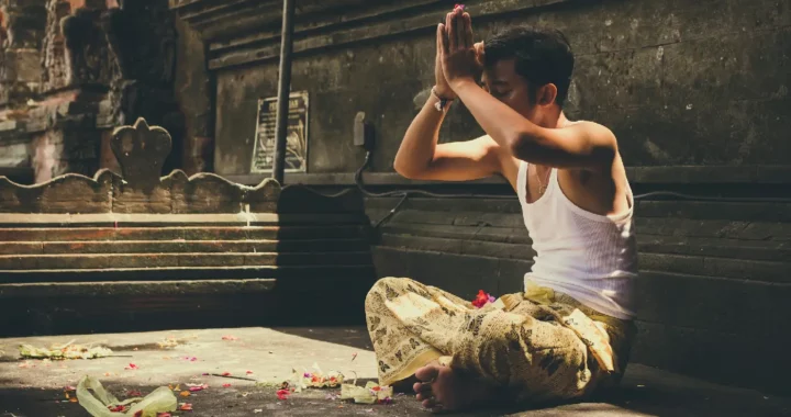 Seorang laki-laki sedang duduk di pura untuk melakukan ibadah agama Hindu.