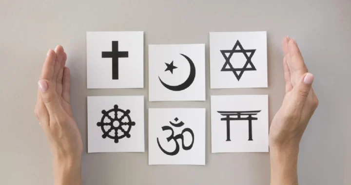 kertas-kertas yang bergambar berbagai simbol agama diantara dua tangan