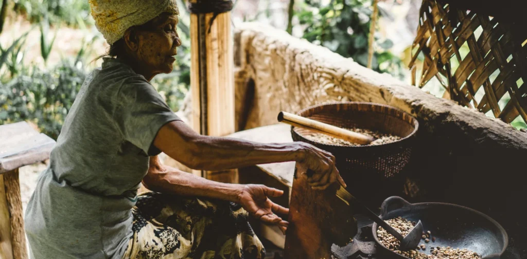 seorang perempuan tua sedang memasak biji-biji di tungku