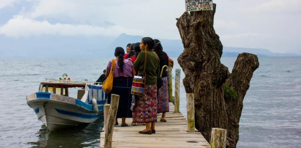 sekelompok perempuan berdiri di tepi danau dengan perahu di samping mereka