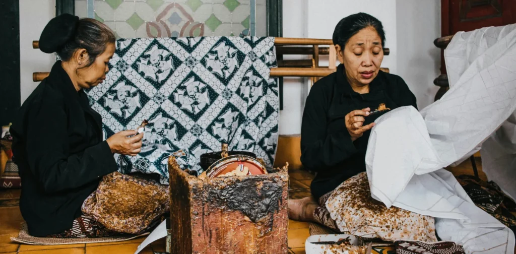 dua perempuan duduk di lantai sedang mencanting batik