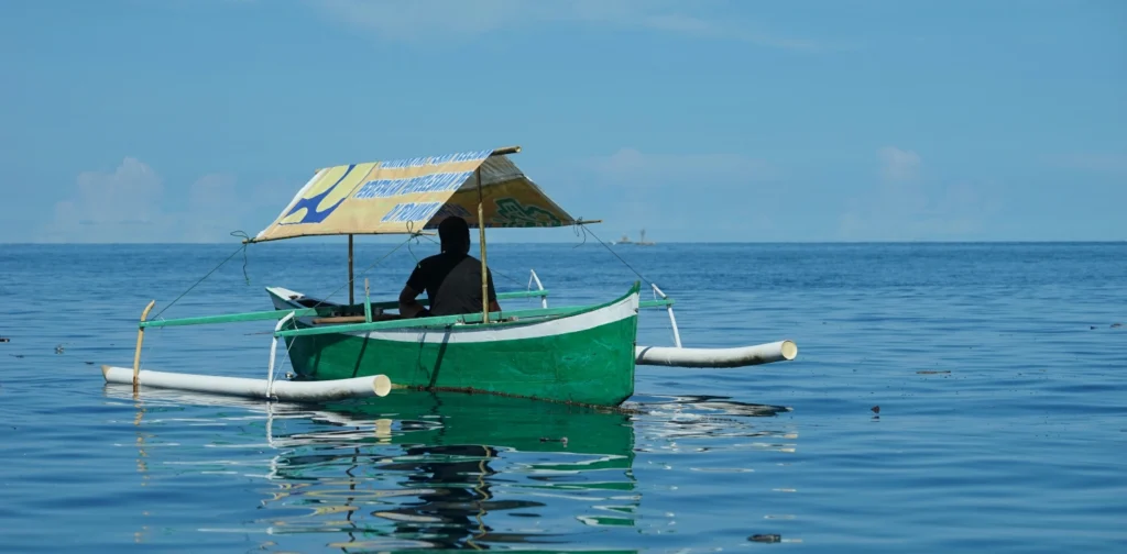 seorang nelayan di sebuah kapal beratap berwarna hijau