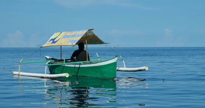 seorang nelayan di sebuah kapal beratap berwarna hijau