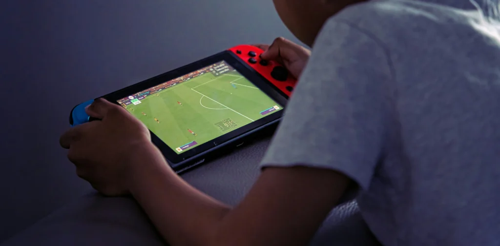 seorang anak bermain game sepakbola dengan gadgetnya