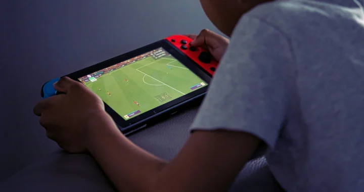 seorang anak bermain game sepakbola dengan gadgetnya