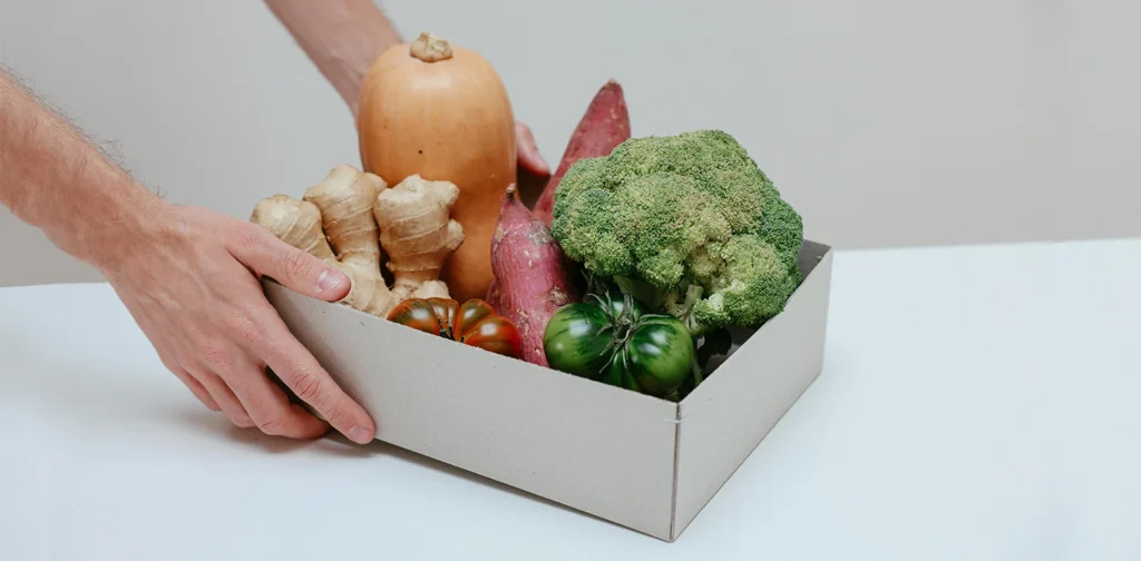 person holding a box of fruits and vegetables