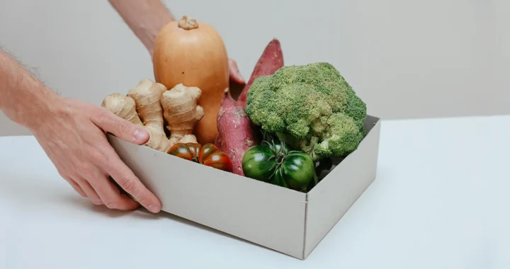 person holding a box of fruits and vegetables