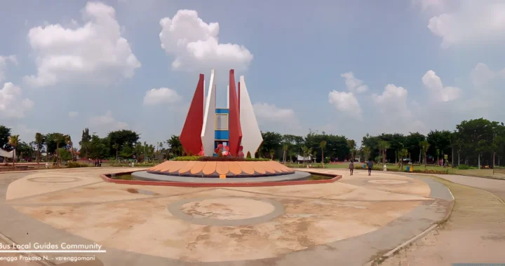 Monumen Alun-alun Mojokerto dikelilingi oleh taman hijau dengan langit biru yang cerah sebagai latar belakang.