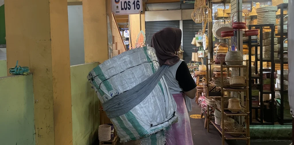 seorang perempuan menggendong barang dagangan